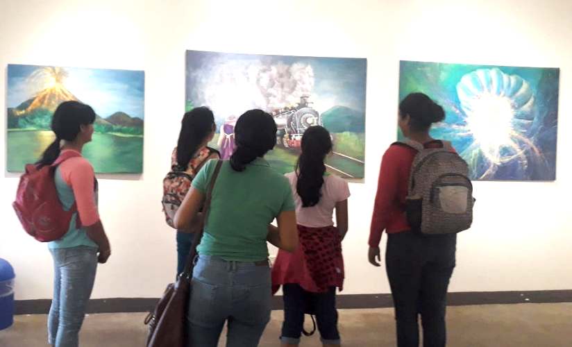 Jóvenes observando los cuadros de la artista Isabella Guillén.