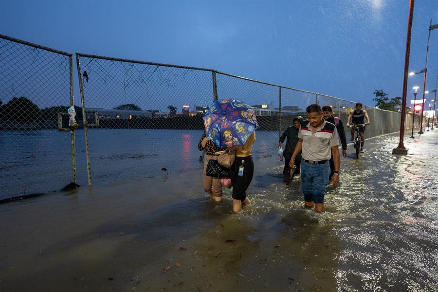 Personas caminan por una vía inundada debido a fuertes lluvias./EFE