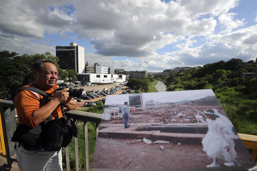 El fotoperiodista hondureño Estalin Irías muestra la foto de una niña vestida de blanco caminando entre los escombros./EFE