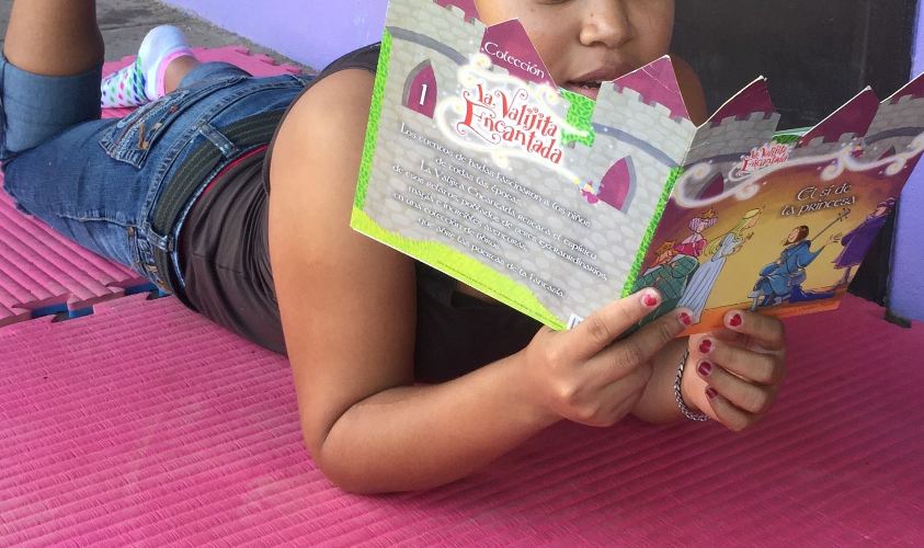 Niña integrante de Casa Alianza, leyendo un libro de cuentos.