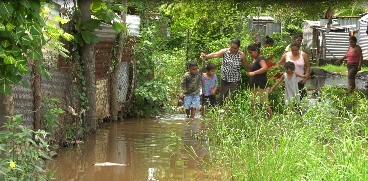 Rosa Reyes junto a sus familiares cruzan la vía de acceso a su hogar. 