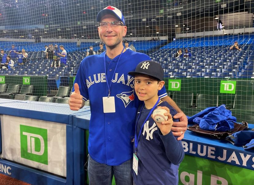 Derek Rodriguez, de 9 años, posa con el aficionado de los Azulejos Mike Lanzillotta, quien le regaló la pelota del cuadrangular de Aaron Judge.